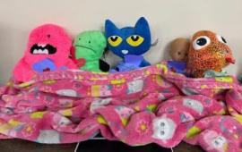 Stuffed animals snuggled under a blanket.