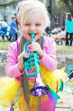 Young child wearing beaded necklaces and blowing a toy horn