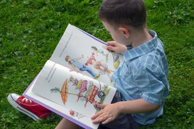Boy reading a picture book outside.