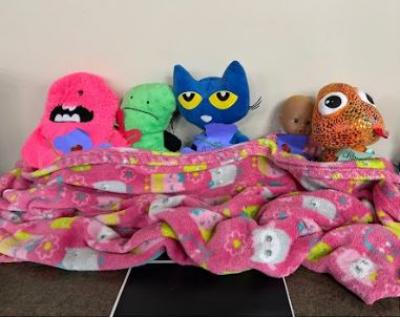 Stuffed animals snuggled under a blanket.