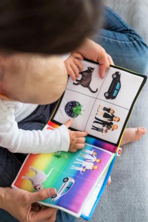 A baby is sitting in a parent's lap with a book.