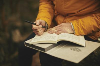 Person holding a pen and writing in a notebook.