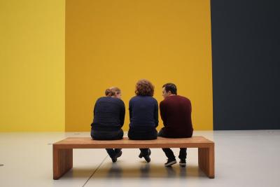 People sitting on a bench in an art gallery.